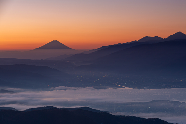 手前に諏訪湖、奥にそびえる富士山が朝日に照らされ、少し赤くなる様子